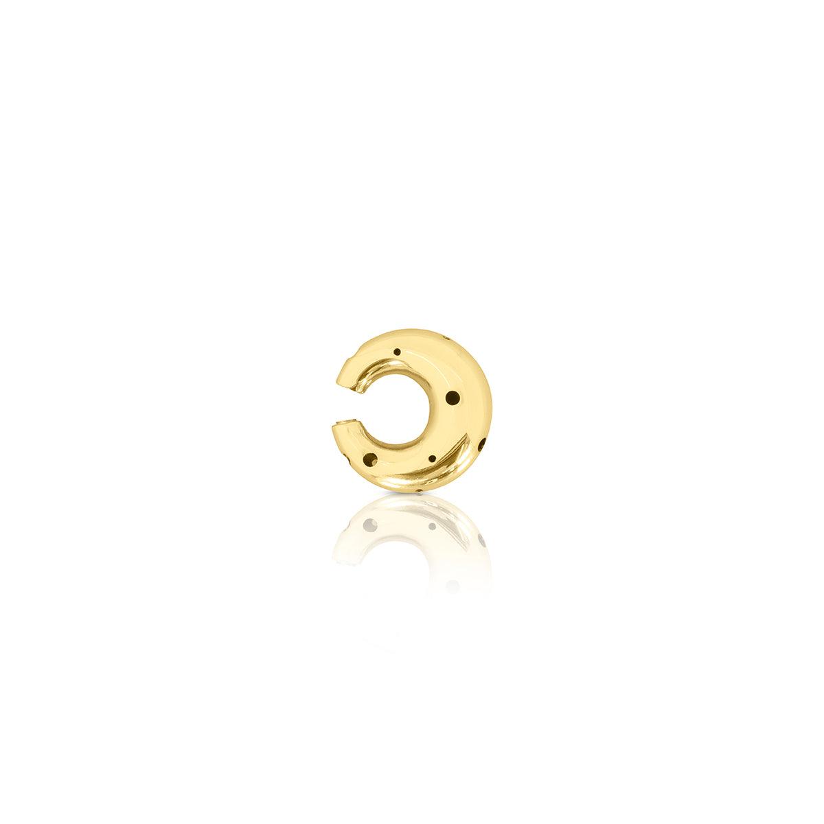 Earcuff de tamaño mediano en forma de luna, disponible en oro o plata, con delicadas perforaciones y un diseño moderno y escultural.