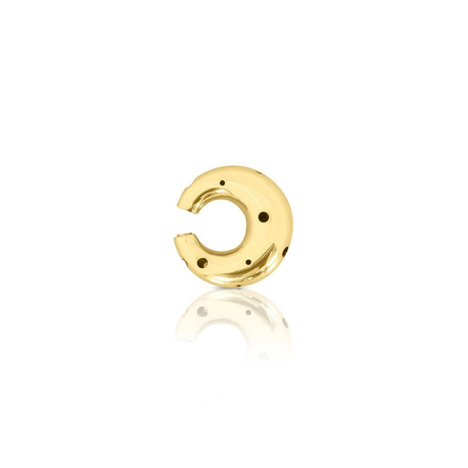 Earcuff de tamaño mediano en forma de luna, disponible en oro o plata, con delicadas perforaciones y un diseño moderno y escultural.