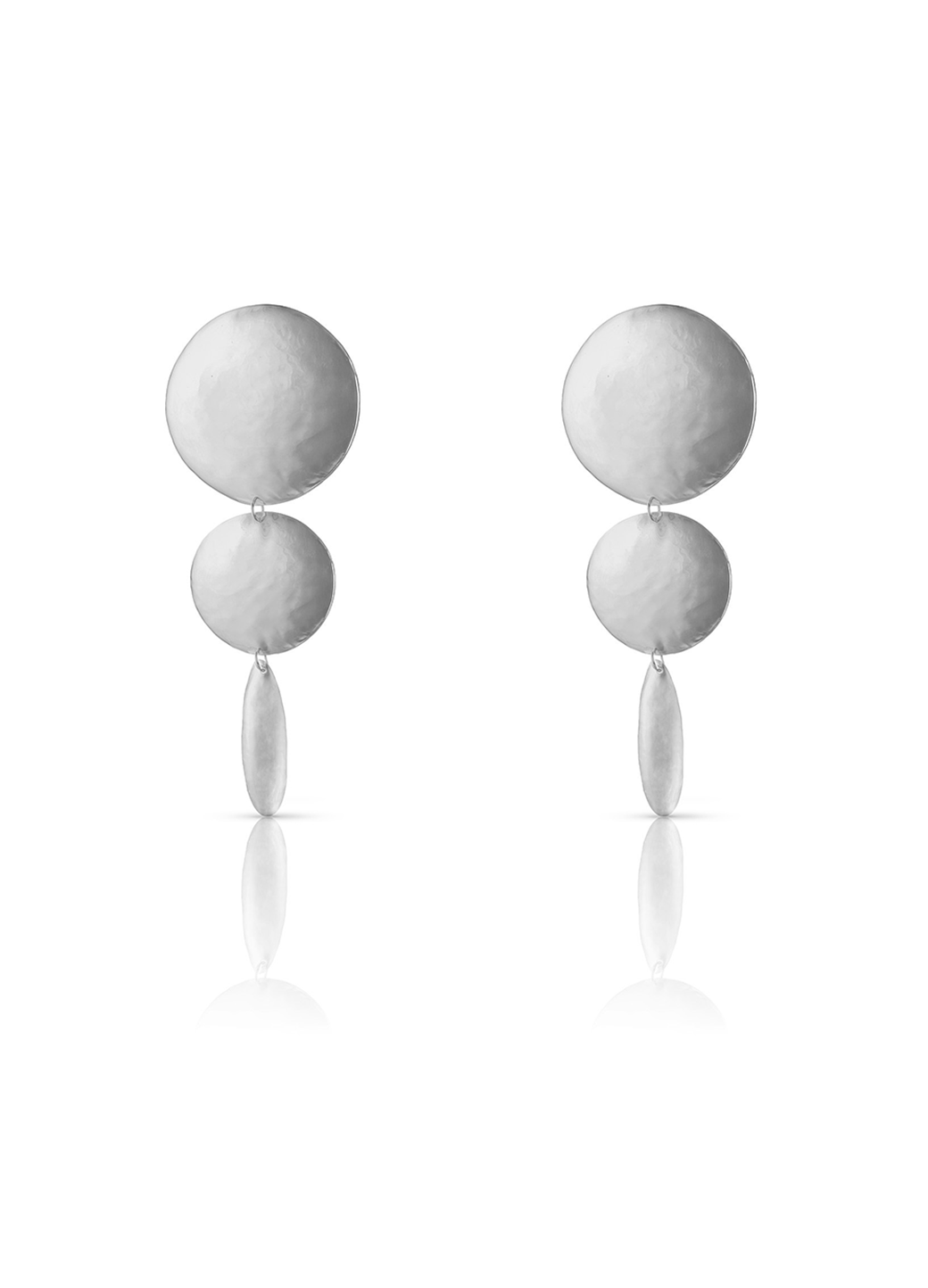 Aretes grandes y largos en plateado compuestos por dos círculos y un óvalo, todos con textura
repujada; una pieza de diseño escultórico de Paula Mendoza.