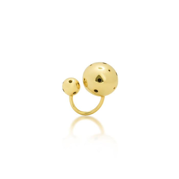Anillo abierto enchapado en oro con dos esferas de diferentes tamaños y delicadas perforaciones, diseñado como una pieza versátil que puede usarse como anillo o earcuff.
